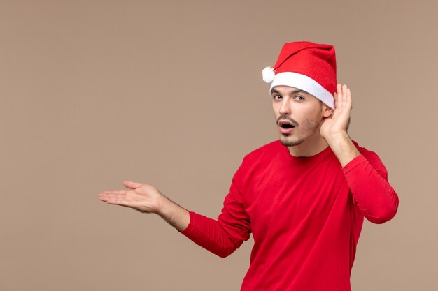 Vue de face jeune homme écoutant attentivement sur fond marron vacances d'émotion de Noël