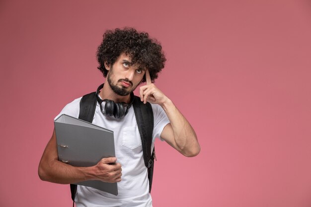 Vue de face jeune homme essaie de se souvenir et tenant un classeur