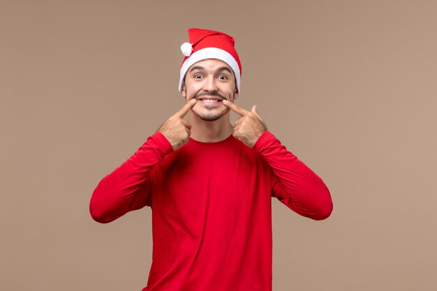 Vue de face jeune homme essayant de sourire sur fond marron émotion vacances mâle