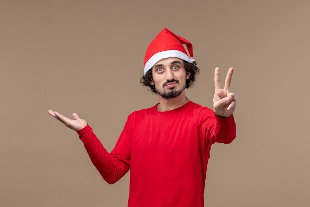 Vue de face jeune homme avec une expression calme sur fond marron vacances émotions Noël