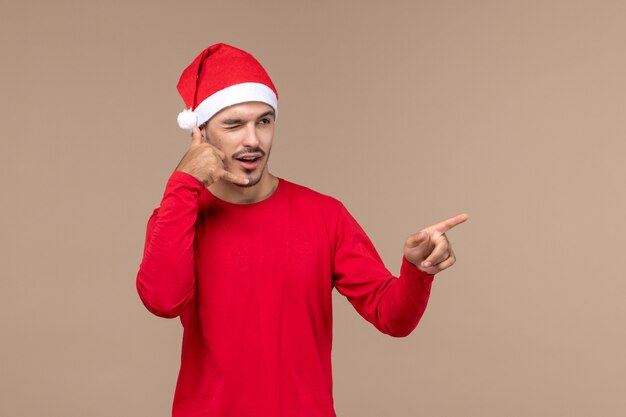 Vue de face jeune homme avec une expression clignotante sur fond brun émotion de vacances de Noël