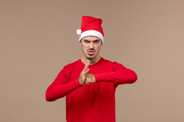 Vue de face jeune homme avec une expression de colère sur fond marron vacances d'émotion de Noël