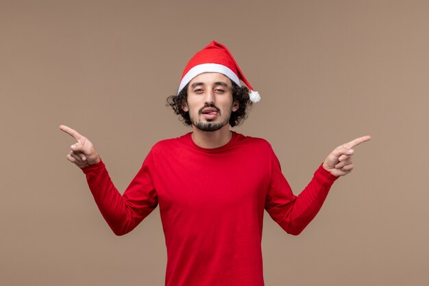 Vue de face jeune homme avec une expression drôle sur fond marron émotion vacances de Noël