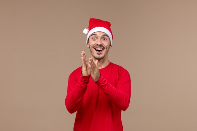 Vue de face jeune homme avec une expression excitée sur fond marron vacances d'émotion de Noël