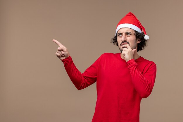 Vue de face jeune homme avec une expression nerveuse sur fond marron vacances Noël émotion