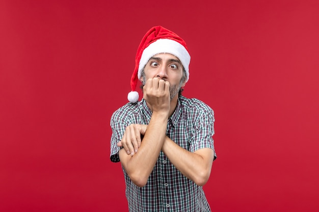 Vue de face jeune homme avec une expression nerveuse sur fond rouge