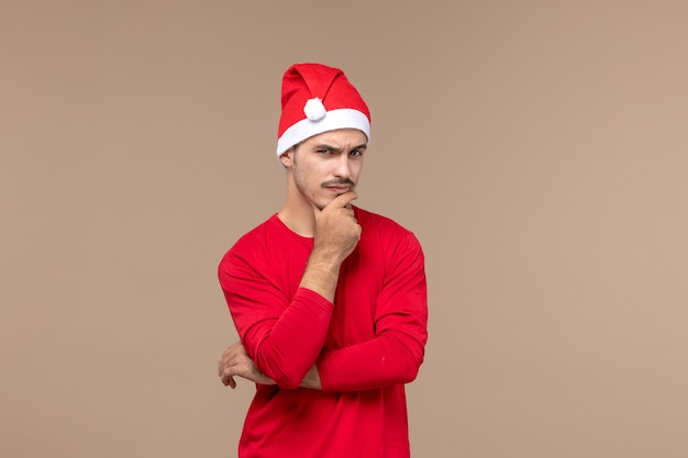 Vue de face jeune homme avec expression de la pensée sur fond marron couleurs de vacances d'émotion masculine