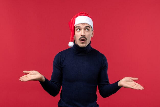 Vue de face jeune homme avec expression de pensée sur fond rouge