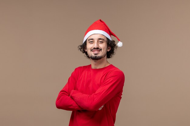 Vue de face jeune homme avec une expression souriante sur un fond marron vacances d'émotions de Noël