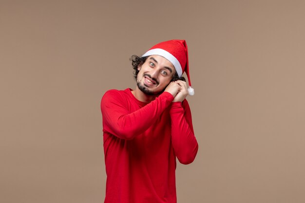 Vue de face jeune homme avec une expression souriante sur fond marron vacances Noël émotion