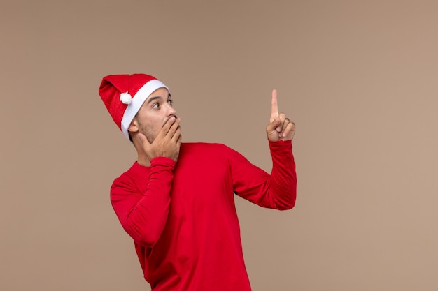 Vue de face jeune homme avec expression surprise sur fond marron vacances de Noël émotion mâle