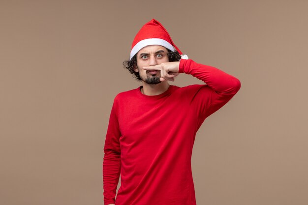 Vue de face jeune homme faisant la moustache sur fond brun émotion vacances de Noël