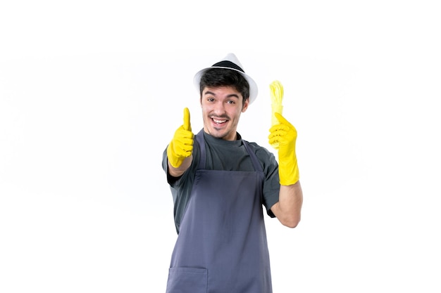 Vue de face jeune homme en gants jaunes tenant des cordes sur fond blanc jardin de fleurs herbe arbre jardinier emploi vert usine de brousse