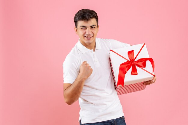 Vue de face jeune homme avec grand cadeau de Noël sur fond rose