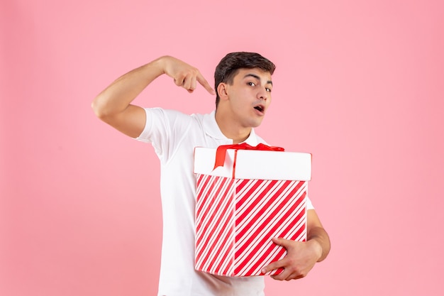 Photo gratuite vue de face jeune homme avec grand cadeau de noël sur fond rose