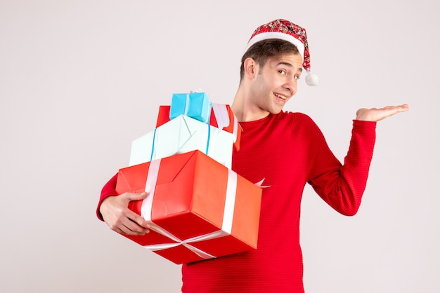 Vue de face jeune homme heureux avec bonnet de Noel debout sur blanc