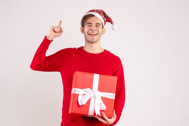 Vue de face jeune homme heureux avec bonnet de Noel debout sur blanc