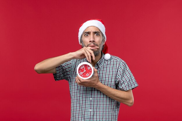 Vue de face jeune homme avec des horloges rondes sur fond rouge