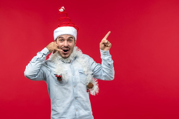 Vue de face jeune homme imitant un appel téléphonique sur un bureau rouge vacances noël