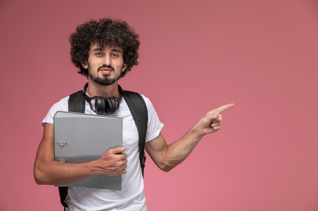 Vue de face jeune homme indiquant sa direction gauche avec reliure et casque