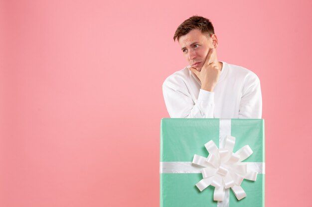 Vue de face jeune homme à l'intérieur présent sur le fond rose