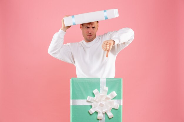 Vue de face jeune homme à l'intérieur présent sur le fond rose