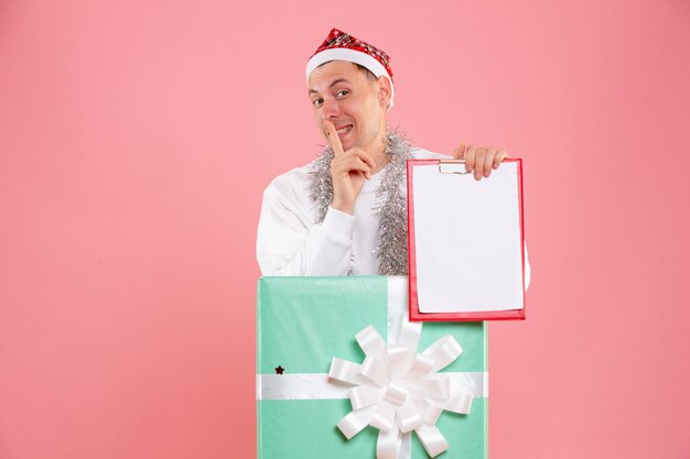 Vue de face jeune homme à l'intérieur présent tenant des notes de fichier sur le fond rose