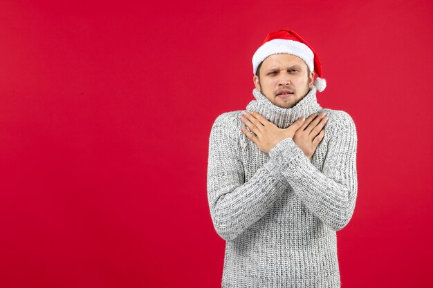 Vue de face jeune homme en jersey chaud grelottant de froid sur fond rouge