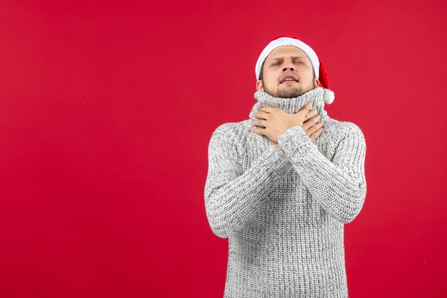 Vue de face jeune homme en jersey chaud sur mur rouge