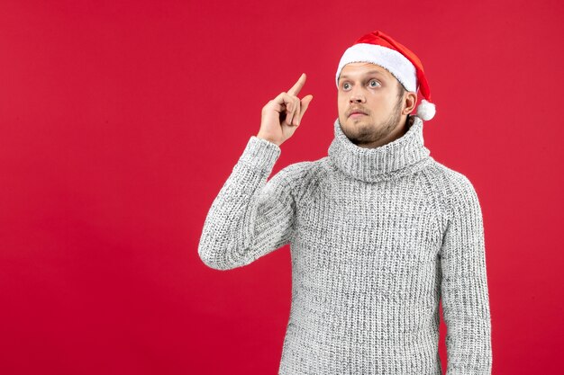 Vue de face jeune homme en jersey chaud sur mur rouge