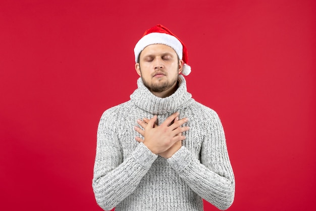 Vue de face jeune homme en jersey chaud sur mur rouge