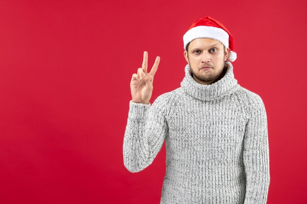 Vue de face jeune homme en jersey chaud sur table rouge