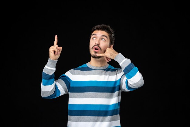 Vue de face jeune homme en jersey rayé bleu imitant un appel téléphonique