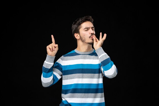 Vue de face jeune homme en jersey rayé bleu pointant vers le haut