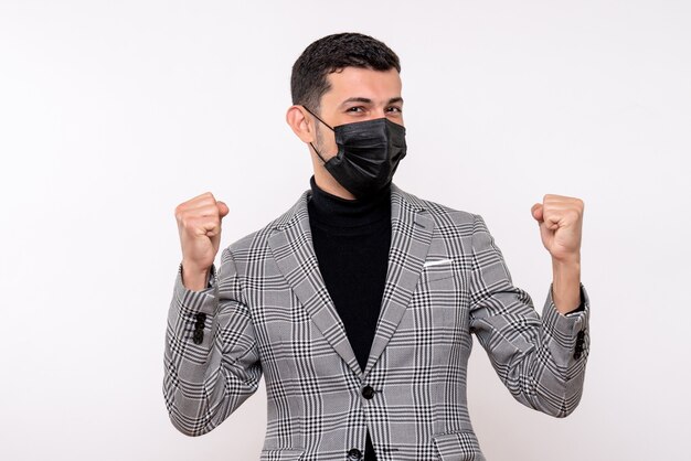 Vue de face jeune homme avec masque noir montrant le geste gagnant debout sur fond blanc isolé