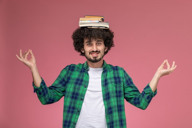 Photo gratuite vue de face jeune homme mettant ses livres sur sa tête