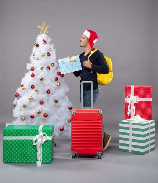 Vue de face jeune homme de Noël avec sac à dos marchant sur gris isolé