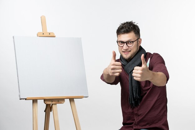 Vue de face jeune homme peintre avec chevalet sur fond blanc