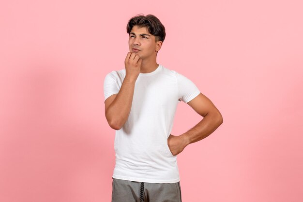 Vue de face jeune homme pensant en t-shirt blanc sur fond rose