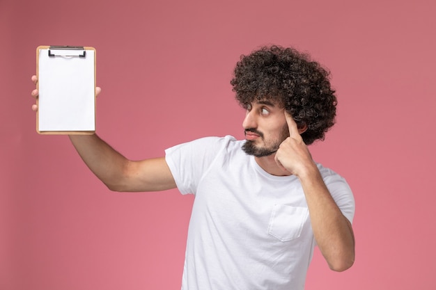 Vue de face jeune homme pensant tout en regardant un ordinateur portable de bureau blanc