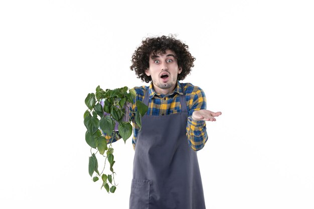 Vue de face jeune homme avec plante verte en pot sur fond blanc arbre plante sol champ de fleurs travail uniforme émotion de brousse verte