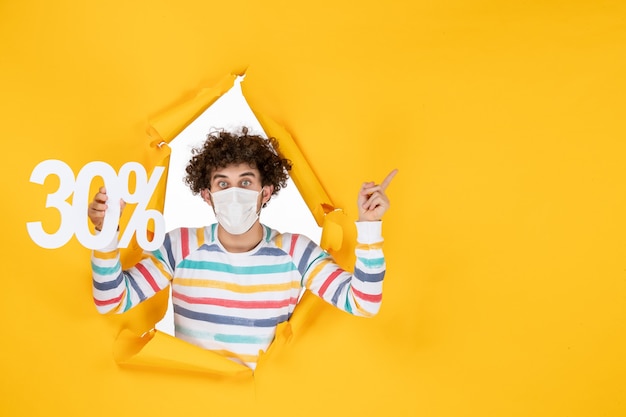 Vue de face jeune homme portant un masque tenant un virus de couleur jaune santé covid- pandémie de photo