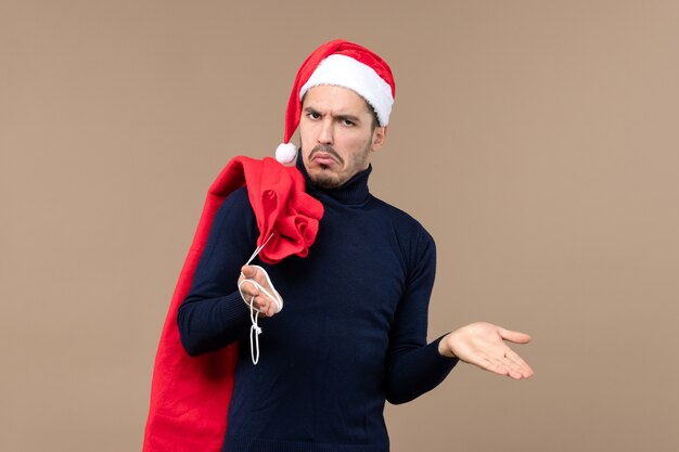 Vue de face jeune homme portant un sac présent sur un bureau marron vacances de noël santa