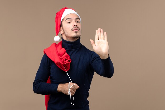 Vue de face jeune homme portant un sac présent, vacances de noël santa