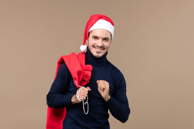 Vue de face jeune homme portant un sac présent, vacances de noël santa