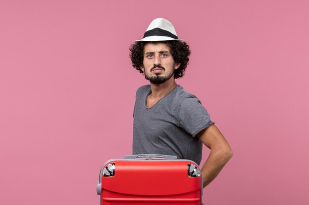 Vue de face jeune homme portant son chapeau et se préparant pour des vacances sur un espace rose