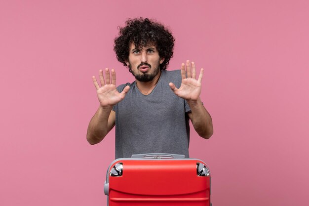 Vue de face jeune homme posant avec une expression confuse sur un espace rose