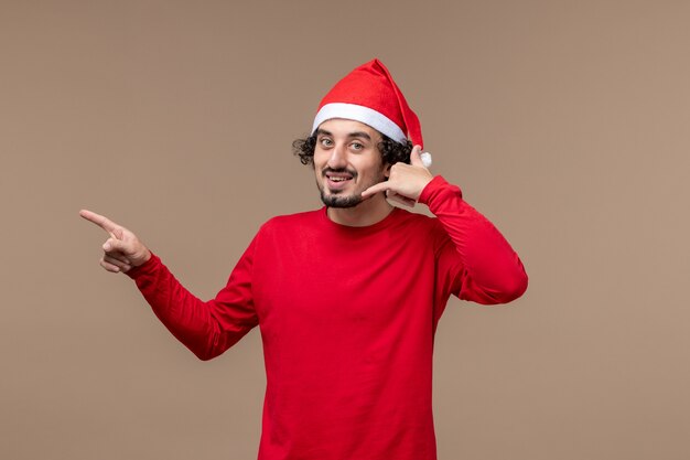 Vue de face jeune homme posant sur fond marron émotions vacances de Noël