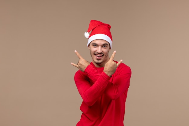 Vue de face jeune homme posant avec sourire sur fond marron émotions vacances mâle