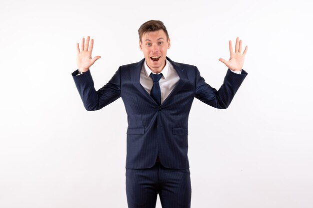 Vue de face jeune homme posant avec un visage joyeux en costume classique sur fond blanc